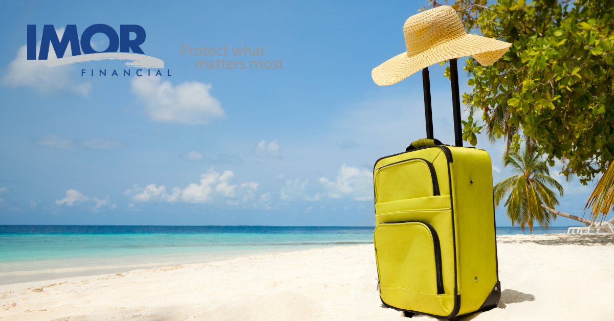 suitcase with sun hat on top in the middle of a sandy beach